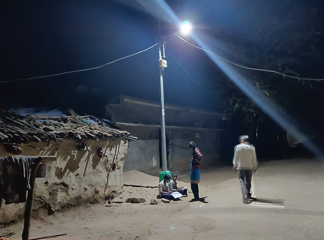 Children in Tuvar Village reading beneath a newly installed streetlight